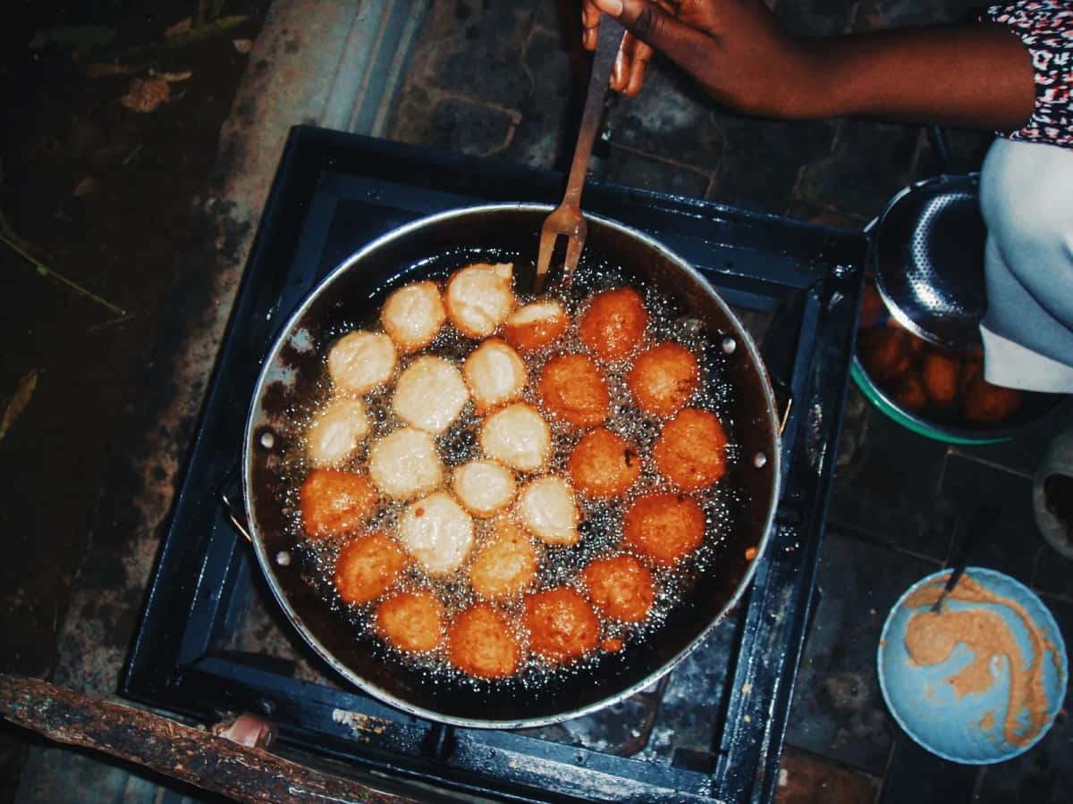 Beignets ronds de pâte de haricot en train de frire dans une grande poêle d'huile
