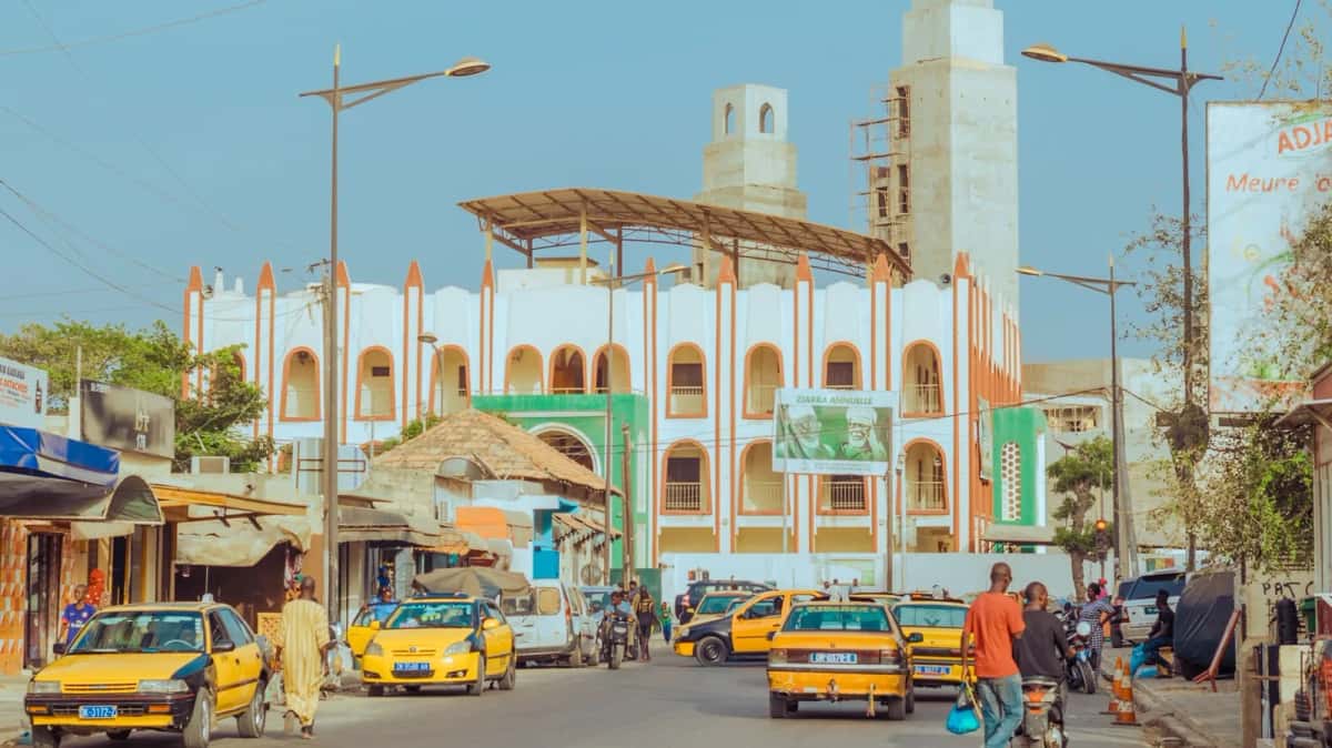 Taxis jaune et noir dans une rue de Dakar, devant une grande mosquée en construction