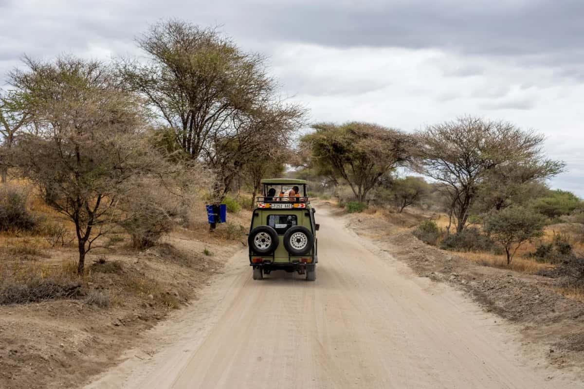 Véhicule 4x4 sur une piste de latérite bordée d'acacias