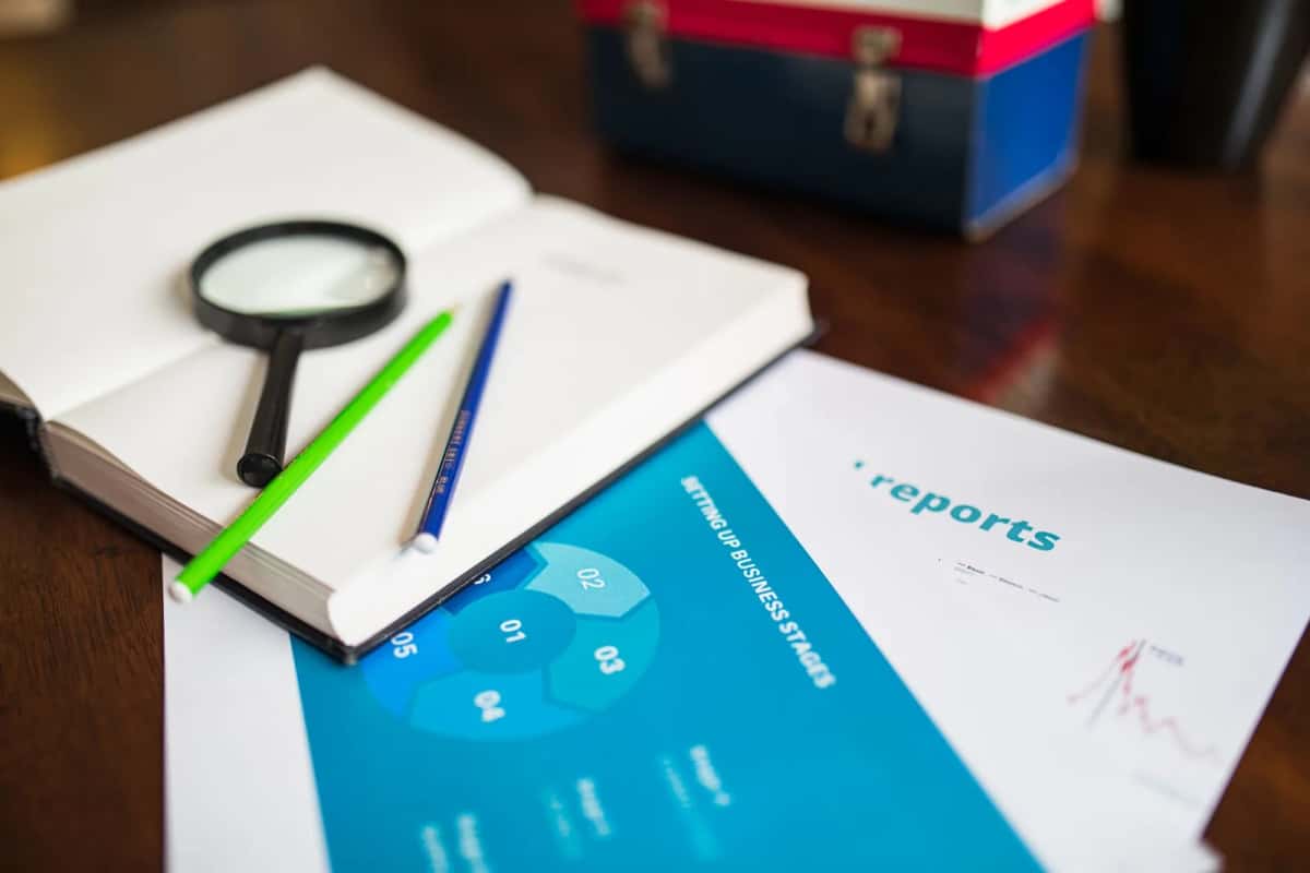 Carnet, loupe et documents posés sur une table de travail