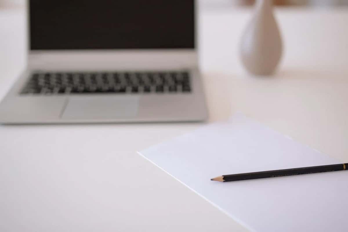 Ordinateur portable, feuille et crayon posés sur un bureau