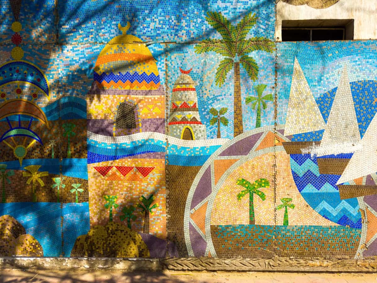 Mur décoré d'une mosaïque colorée aux palmiers, voiles et motifs géométriques